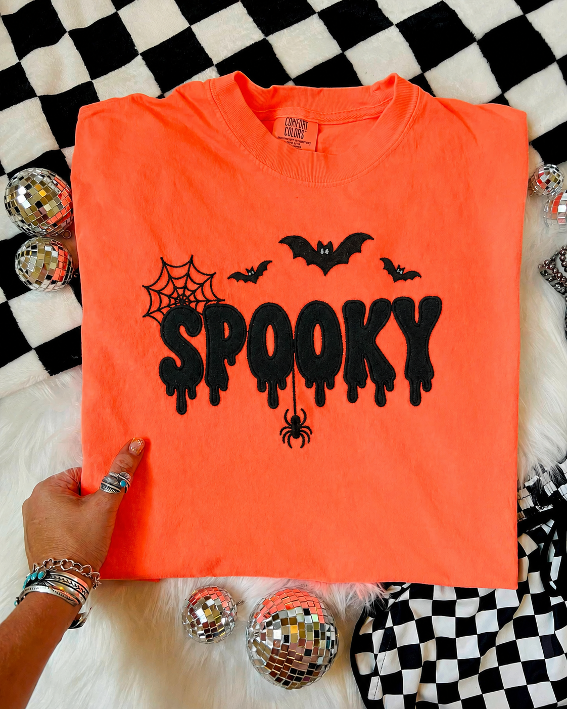 An orange short-sleeve t-shirt with a black 'SPOOKY' Embroidered applique and spider/bat motifs